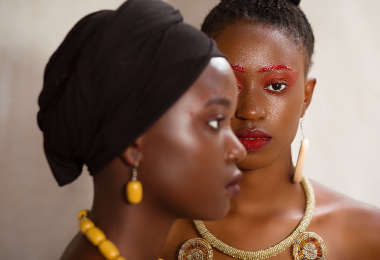 Stylish portrait of two African women with bold accessories and creative makeup.