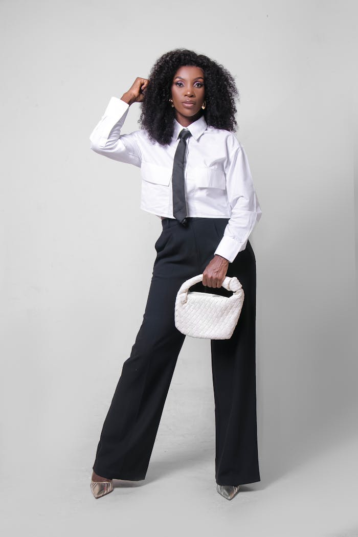 Stylish woman dressed in a modern black and white outfit holding a chic purse.