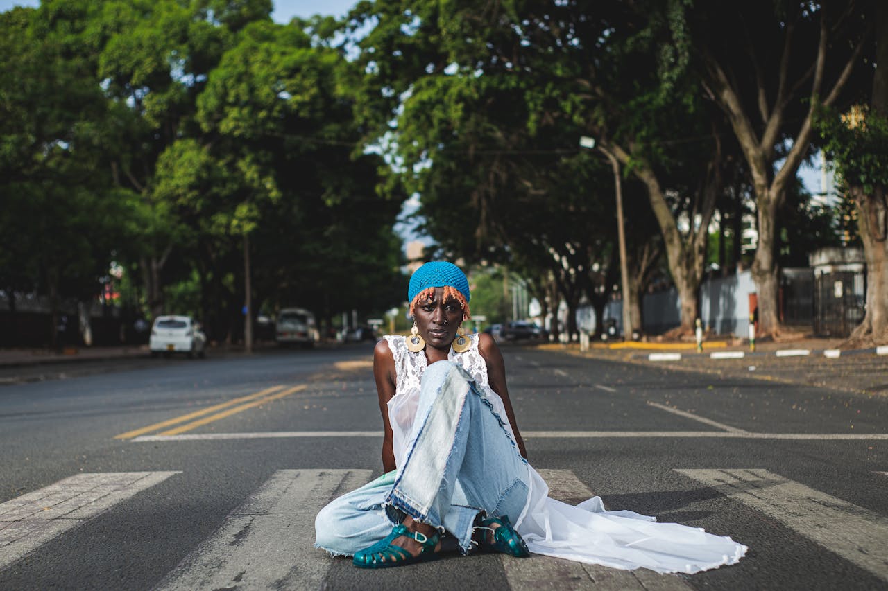 Fashionable woman sitting on a zebra crossing in Nairobi, Kenya, wearing vibrant attire.