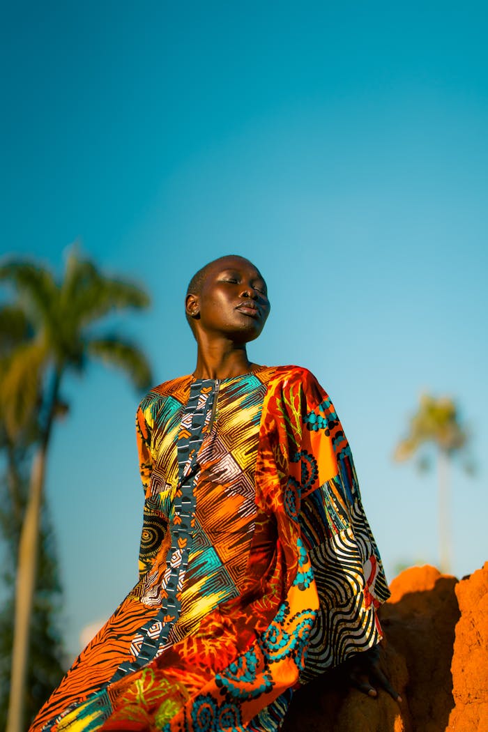 A person in traditional colorful clothing basks under Uganda's bright sun with clear skies.
