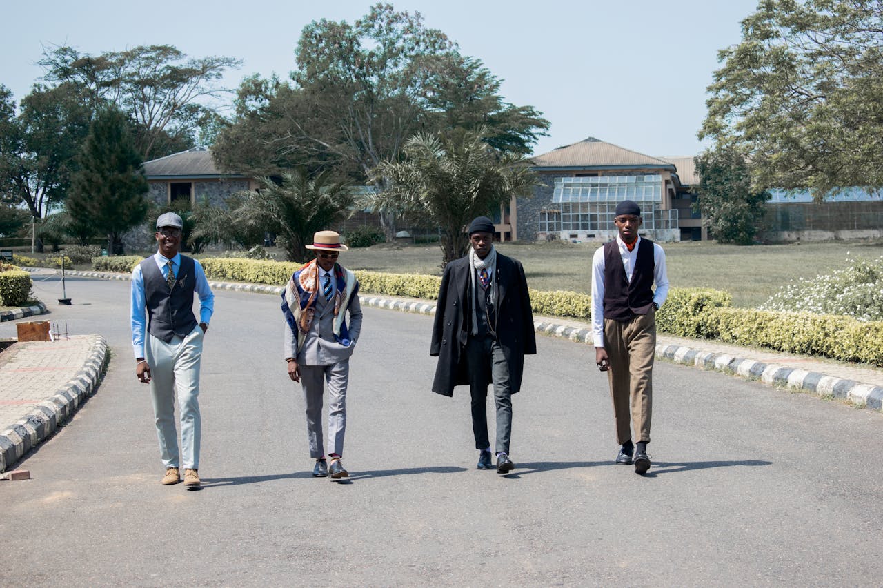 Four men in fashionable attire walking outside in Nigeria. Urban style meets nature.